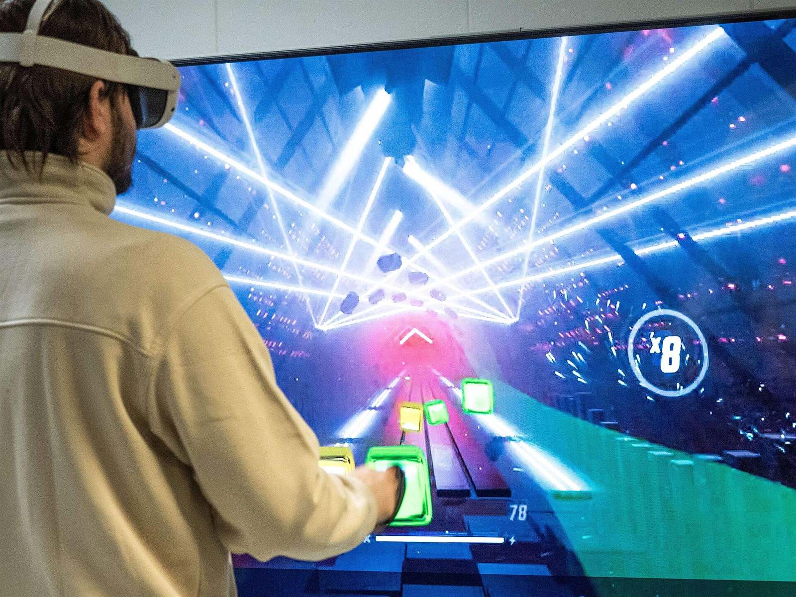 Гравець у VR-шоломі перед телевізором, на екрані ритм-гра в синіх тонах